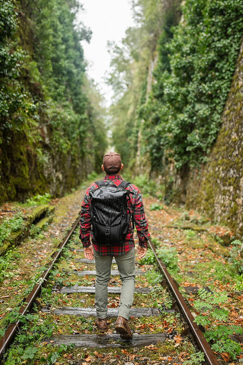 man exploring old train tracks in nature