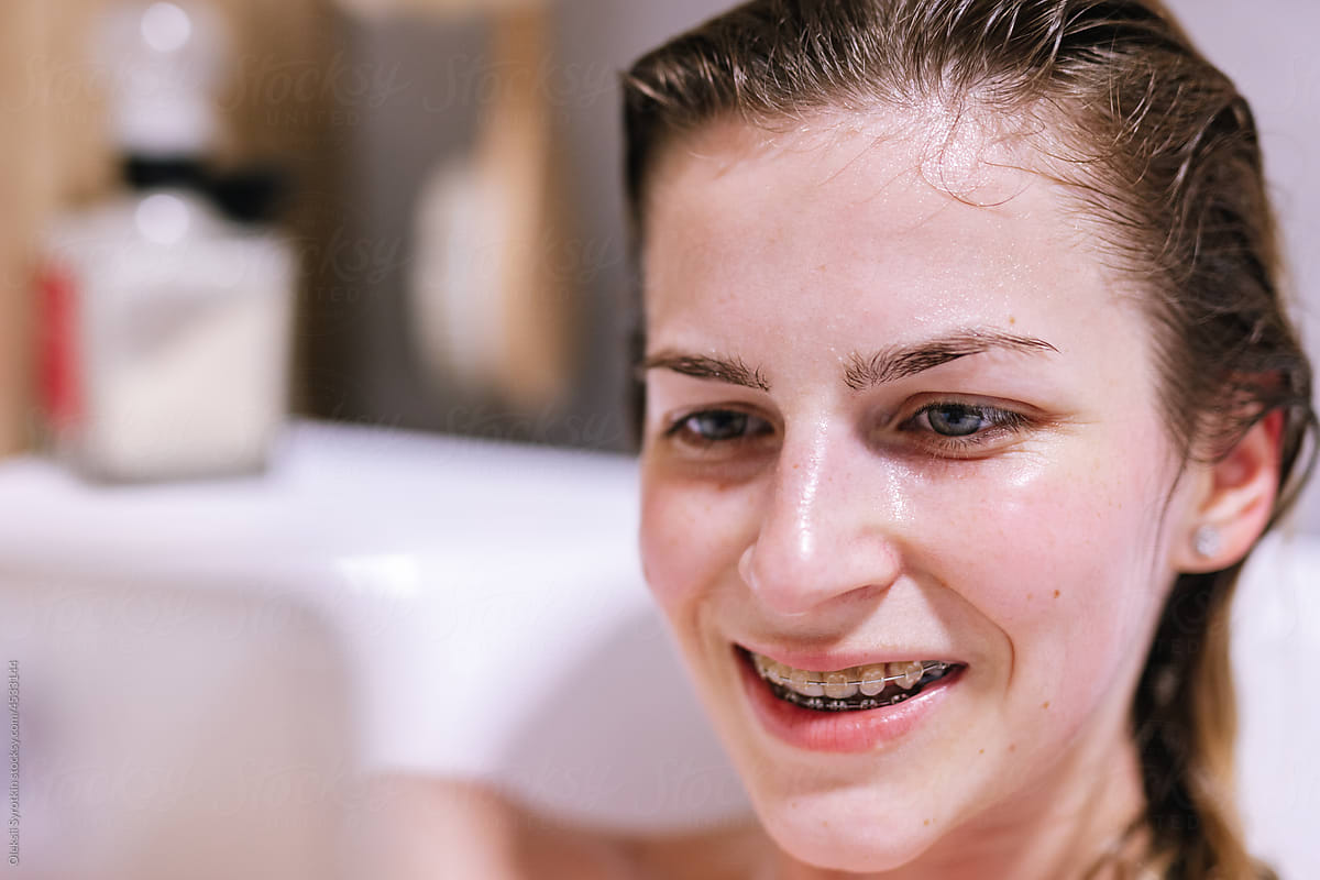 Face of woman relaxing in bath and looking with interest on something