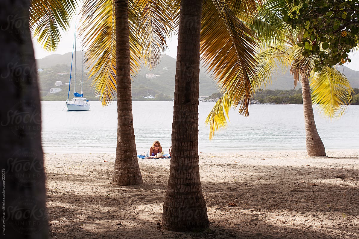 Woman relaxing and reading on the beach with palm trees