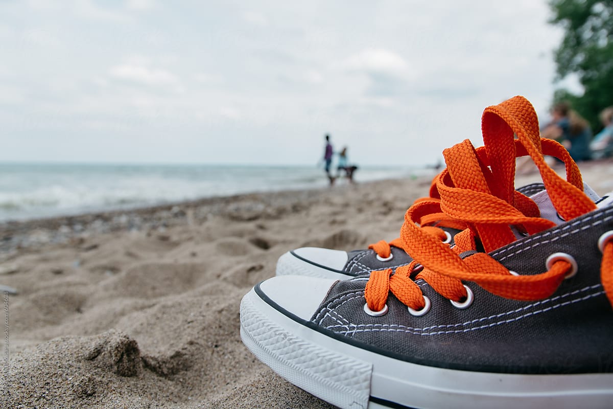 Tennis shoes with orange laces on a beach
