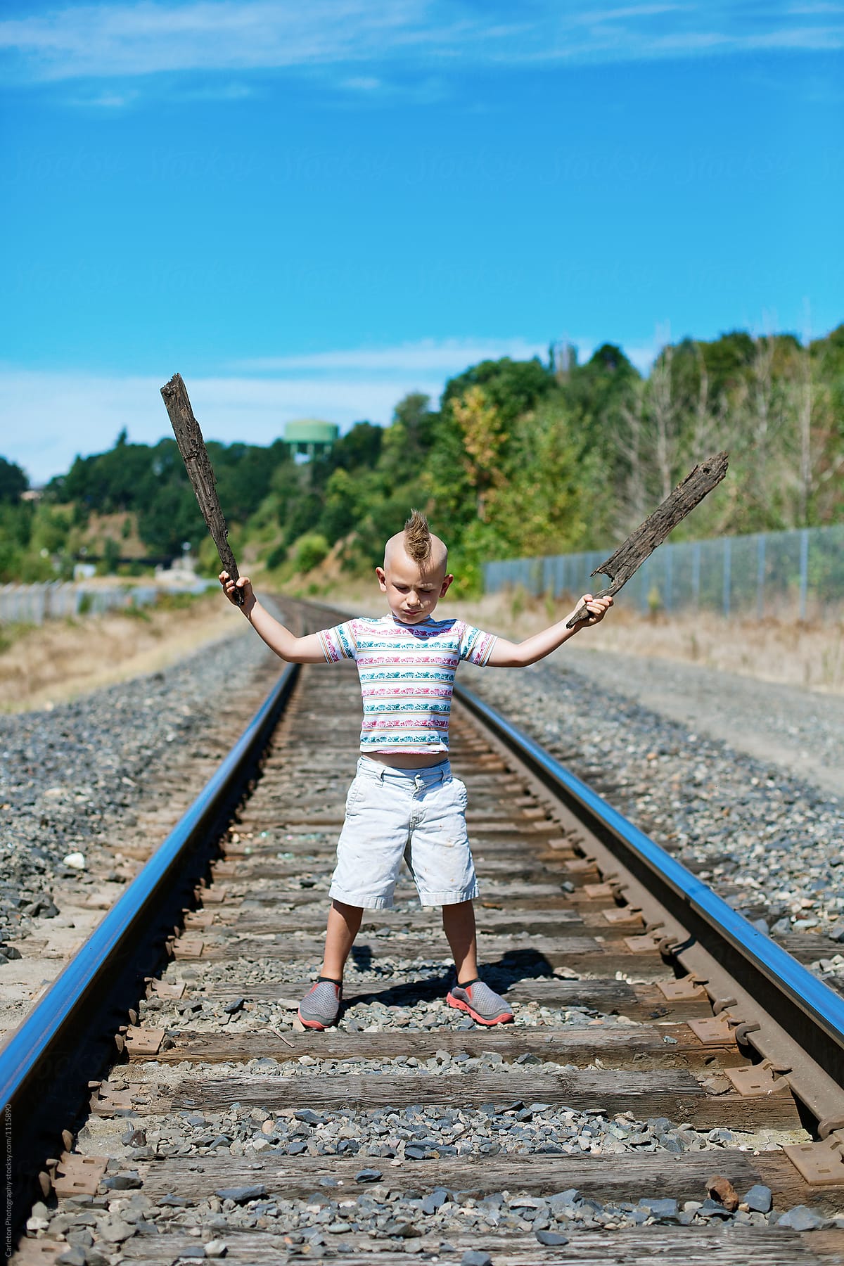 Five year old boy with mohawk playing between railroad tracks