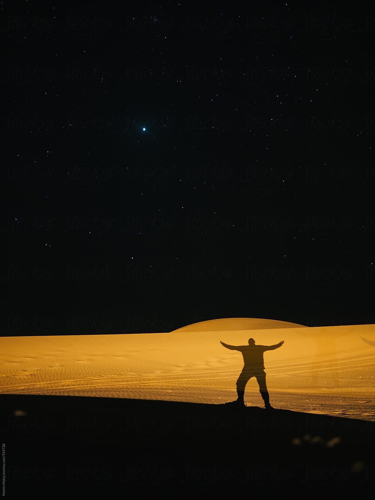 Shadow in the desert with spread hands under the stars