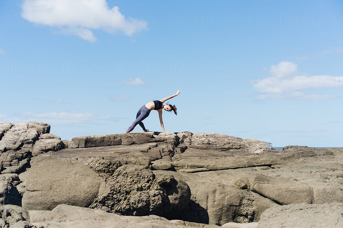 Woman Practicing Pilates On The Rocks.