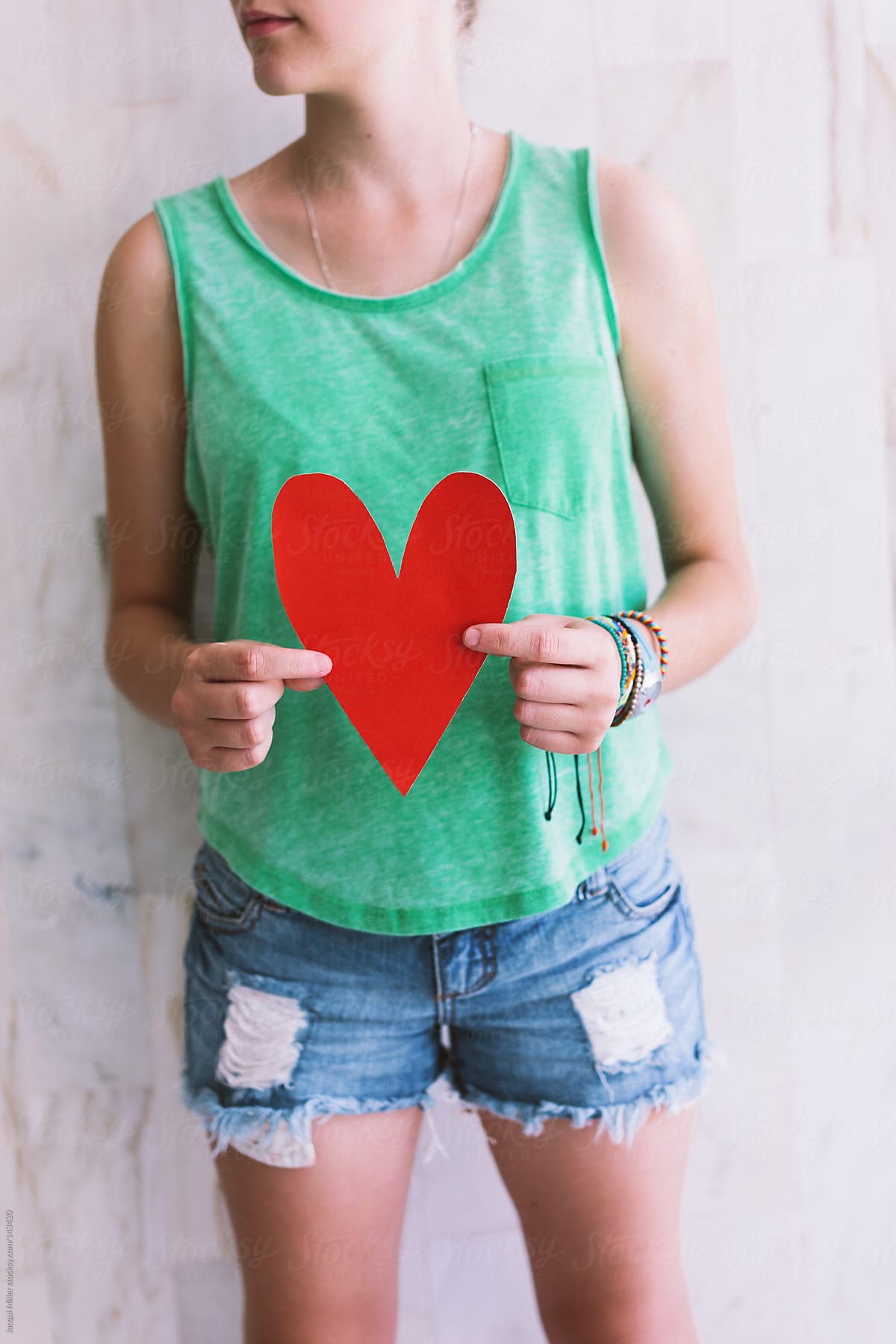 Teen girl holds a red paper heart in front of her body