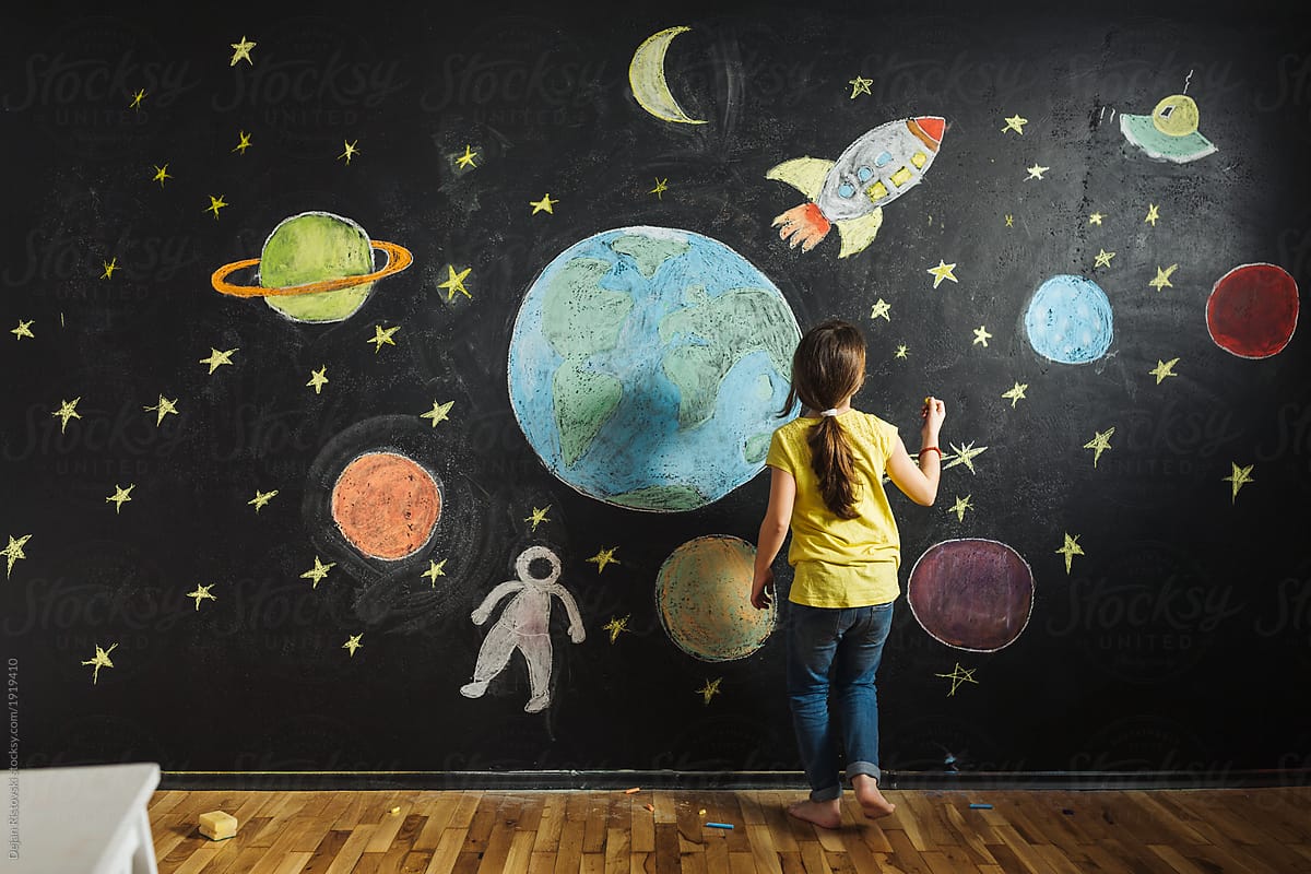 Young girl decorating the black wall with drawings