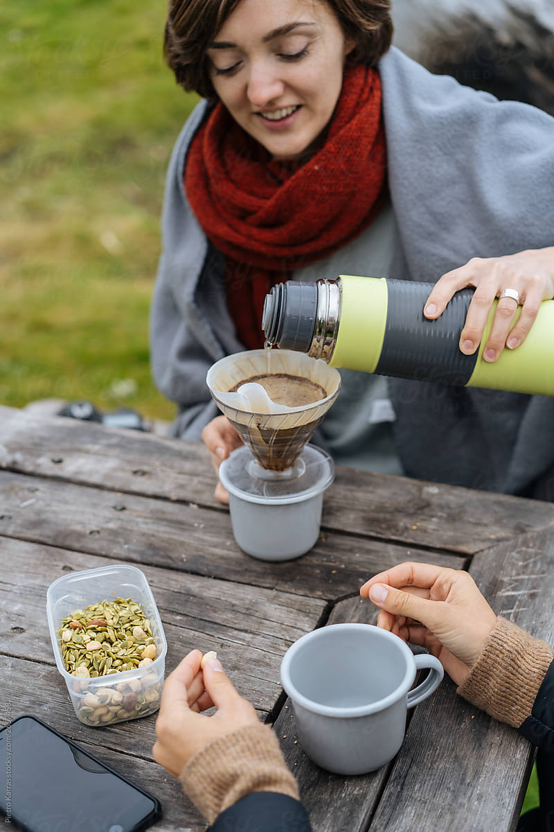 Woman pouring tea from thermos into cup