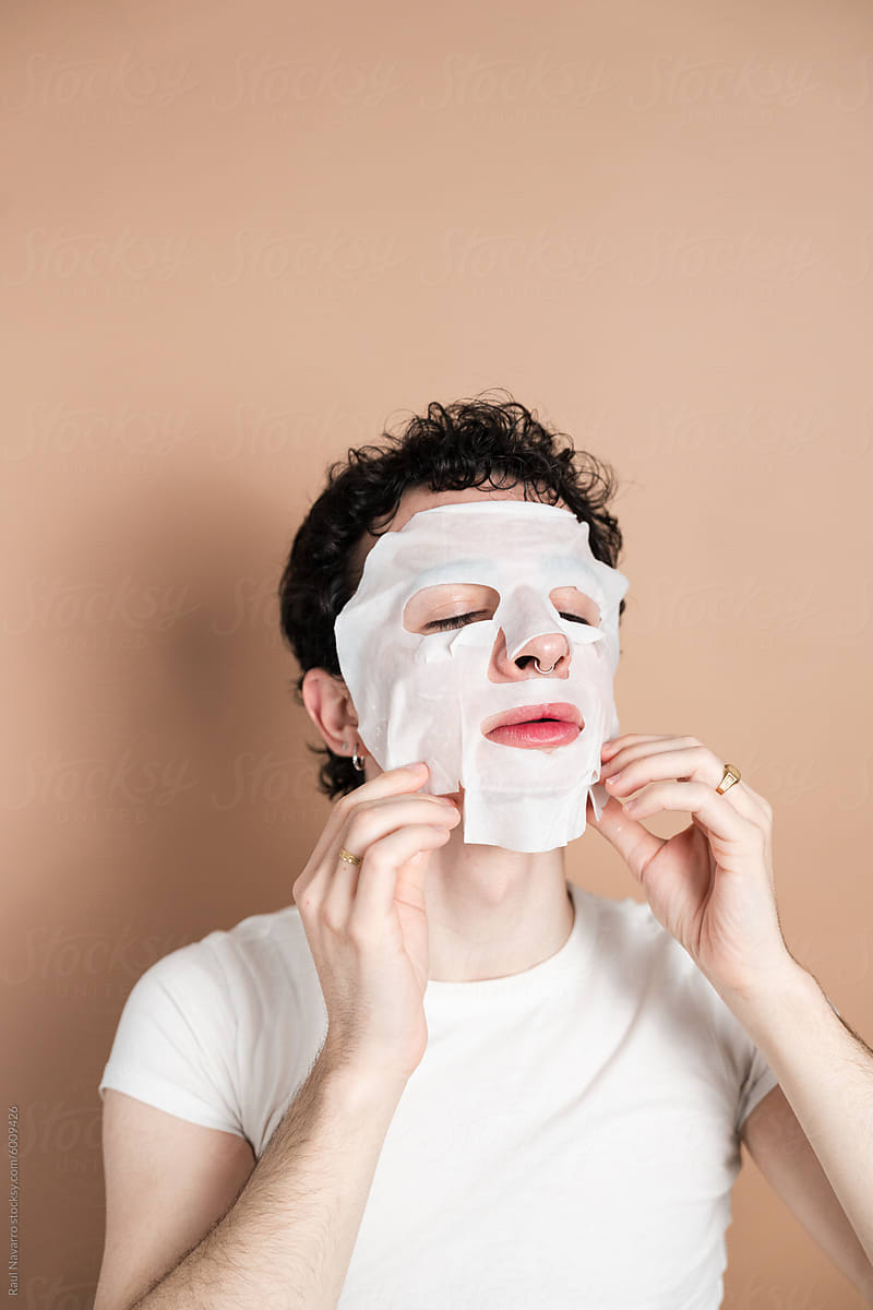Young man applying facial mask