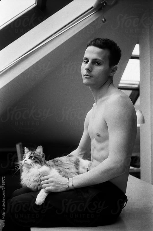 A portrait of a young man with a cat