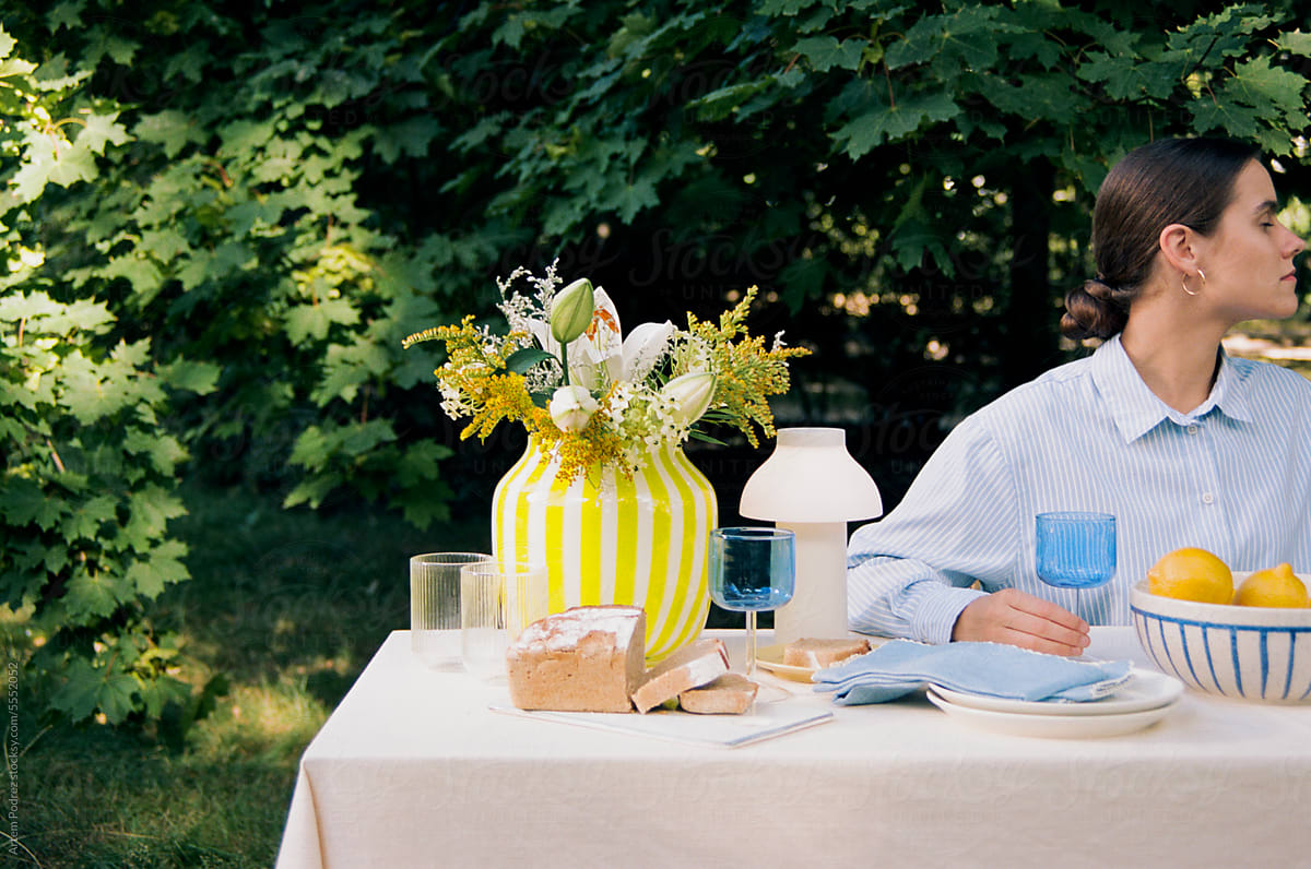 A woman is sitting at a table with a modern outdoor picnic decor.