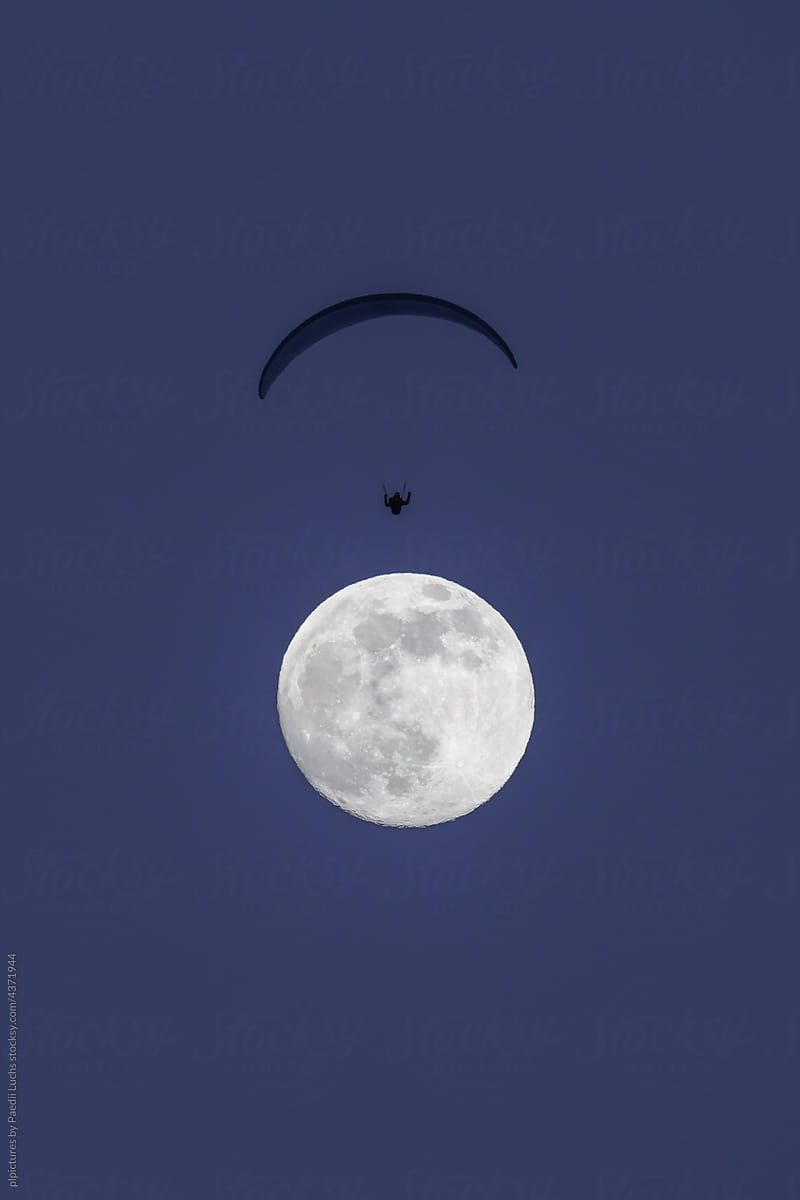 Paraglider flying over the moon.