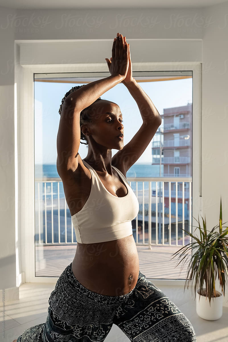 Black woman expecting baby practicing yoga in morning