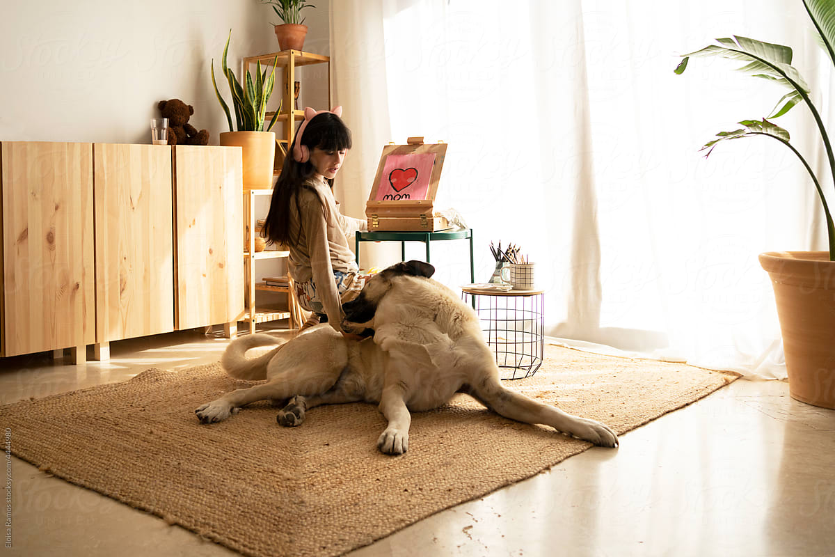 Girl drawing with her dog at home