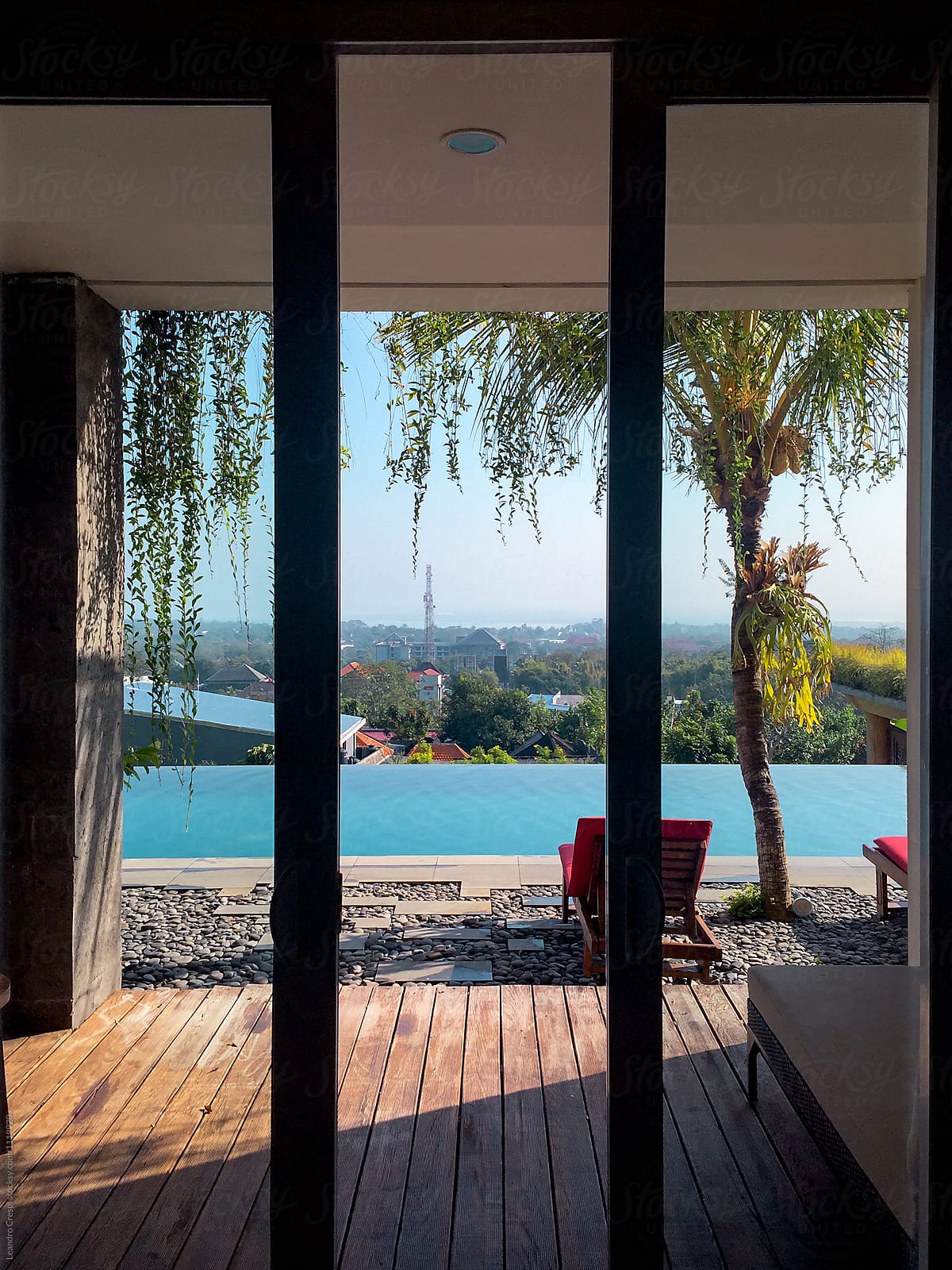 Windows views of a infinite pool and city from inside of a house
