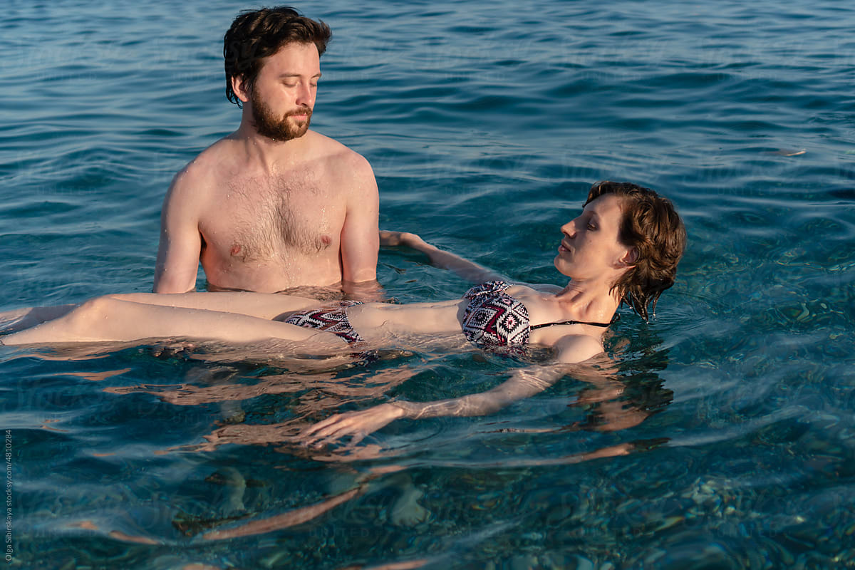 Man hold woman floating in sea