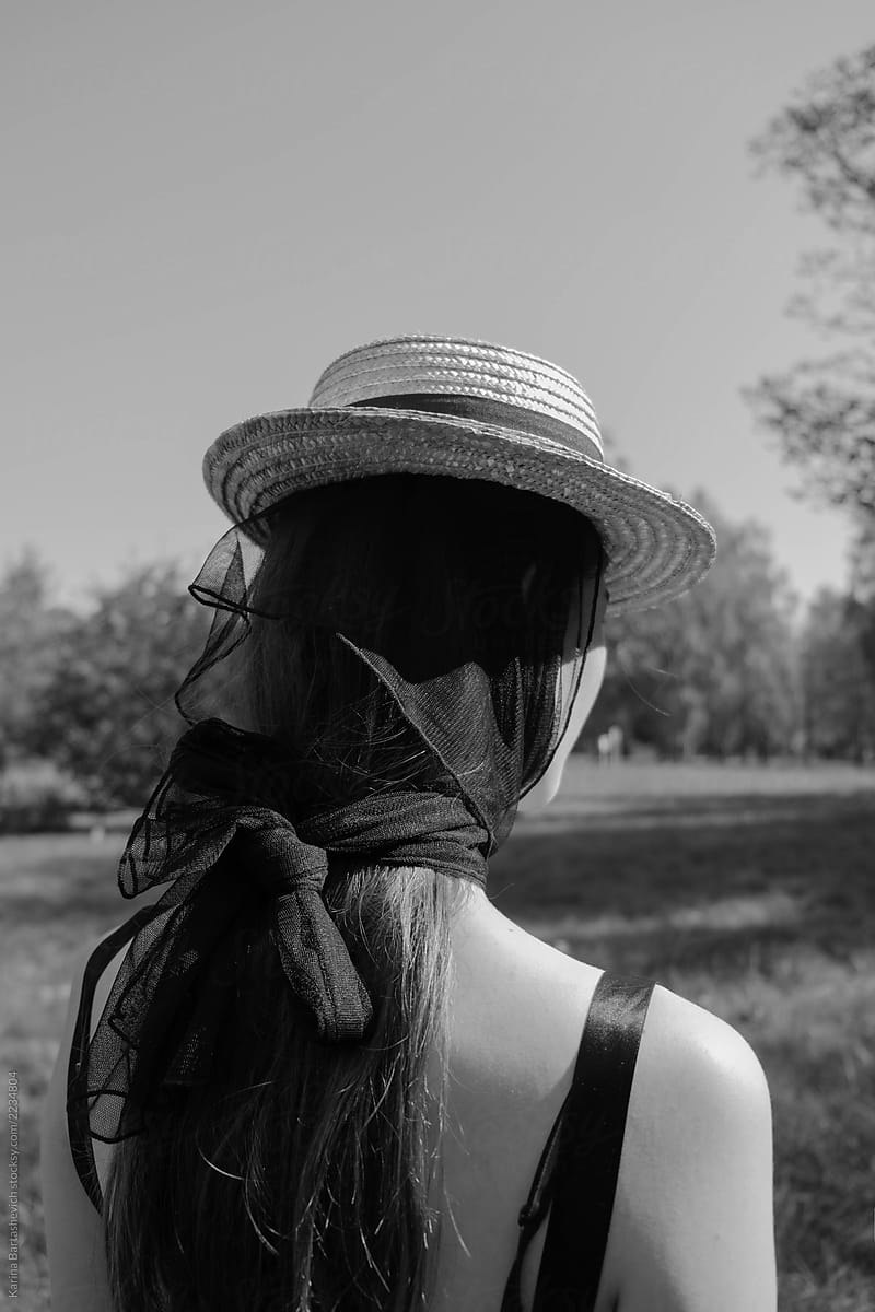 black and white portrait from the back of a retro girl in a dress and a hat in the Park
