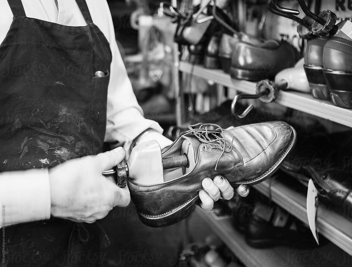 Cobbler stretching a leather shoe with a hand stretcher