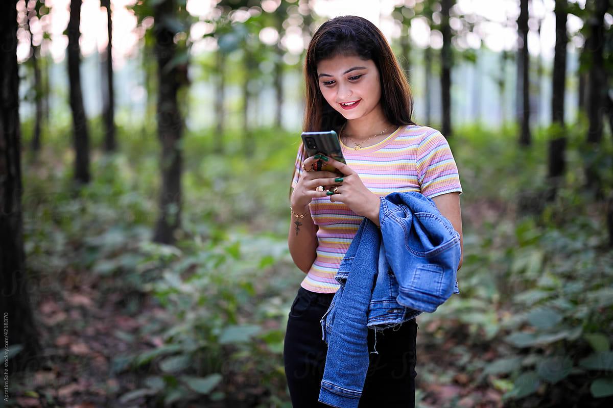 Beautiful young girl surfing smartphone in forest