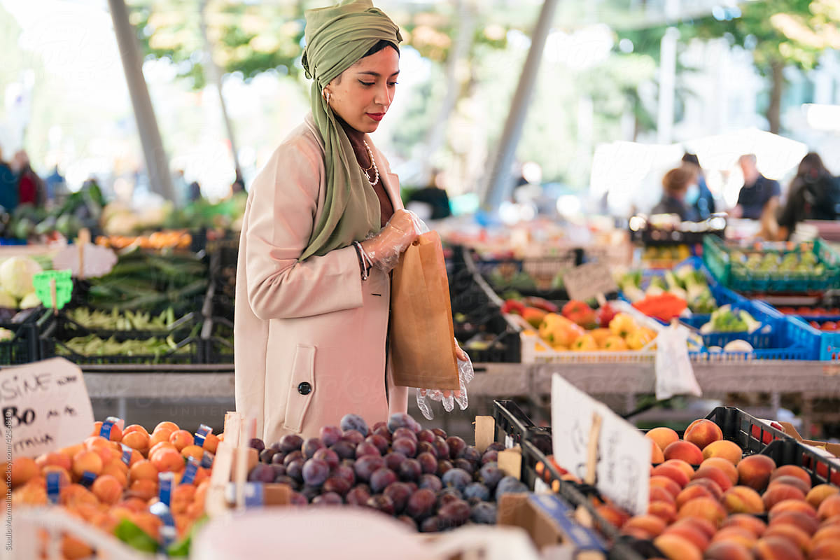 Muslim female buyer examining fruits