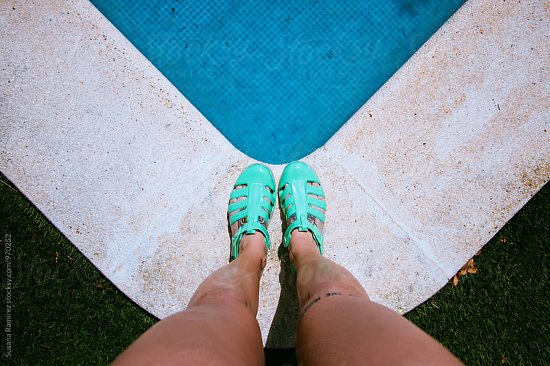 Woman\'s legs on the edge of the pool with sandals