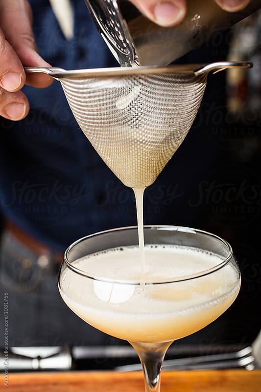 Bartender straining drink