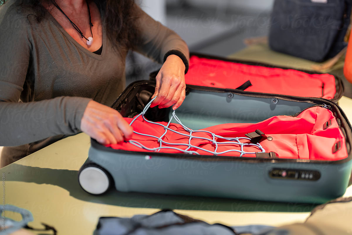 Unrecognizable woman putting net on inside of suitcase