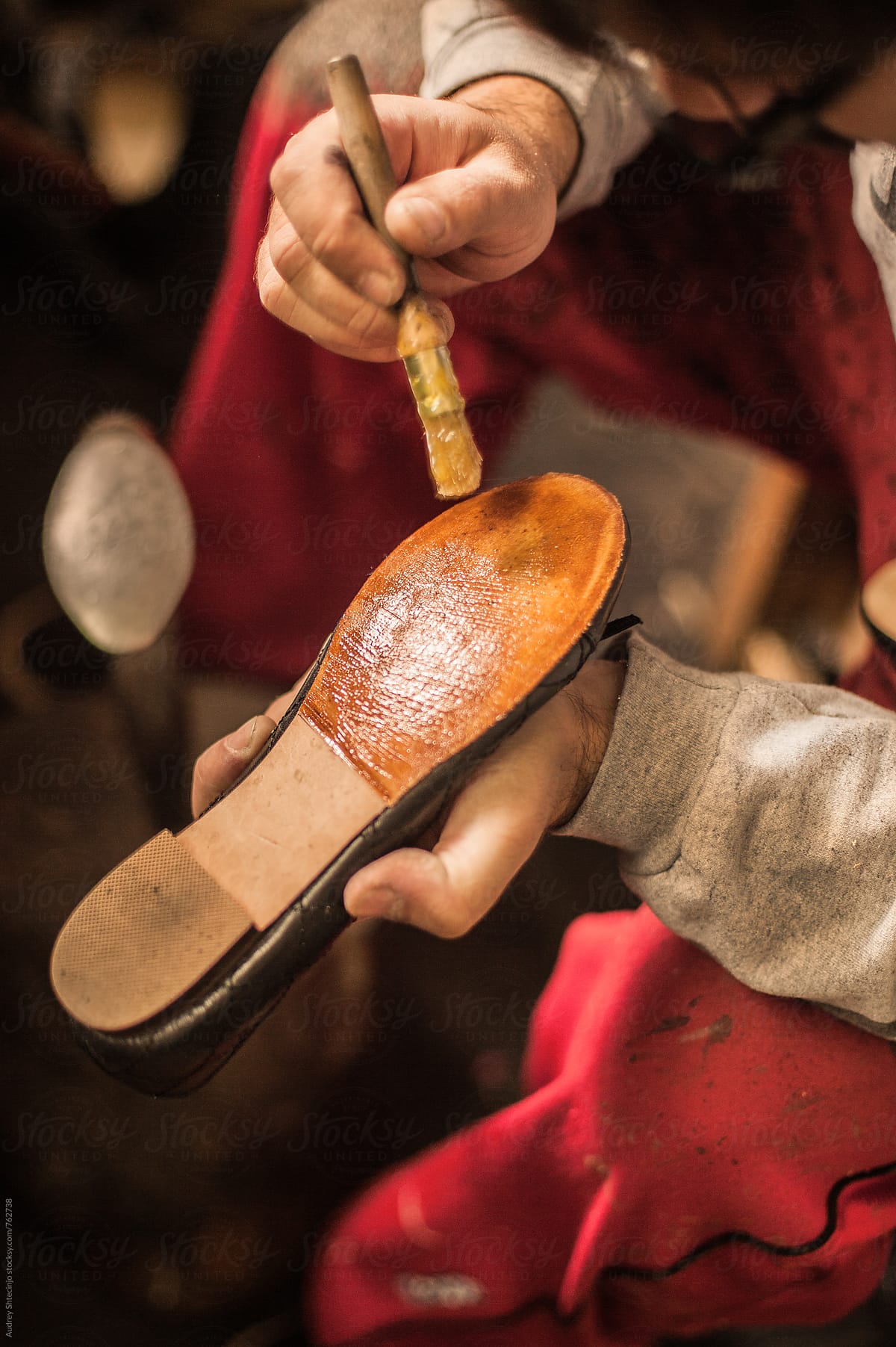 Close up/detail of shoemaker putting glue on shoes.