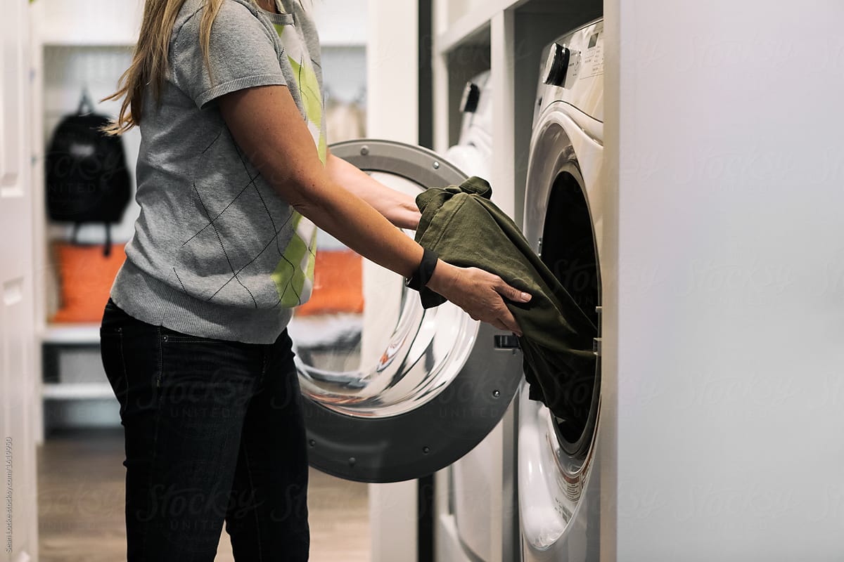 Home: Woman Putting Clothes Into Washer