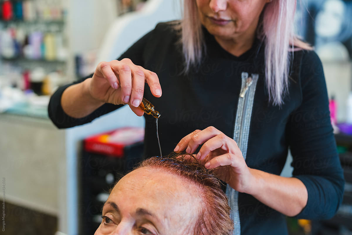 Hairdresser Pouring Hair Medicine on Senior Woman