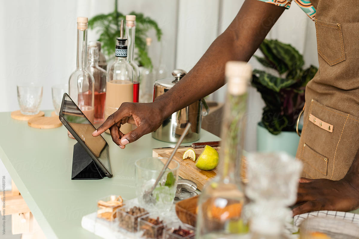 Cropped mixologist using tablet at workplace