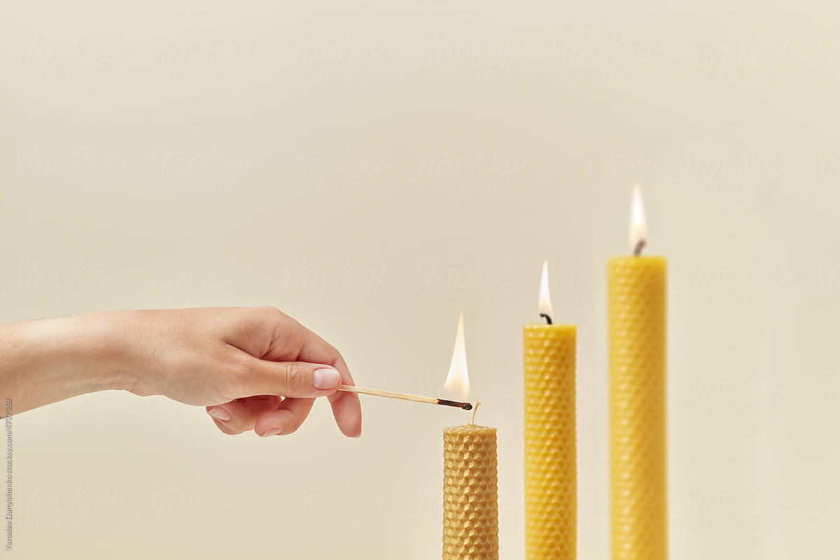 Handmade beeswax candles lit by woman.