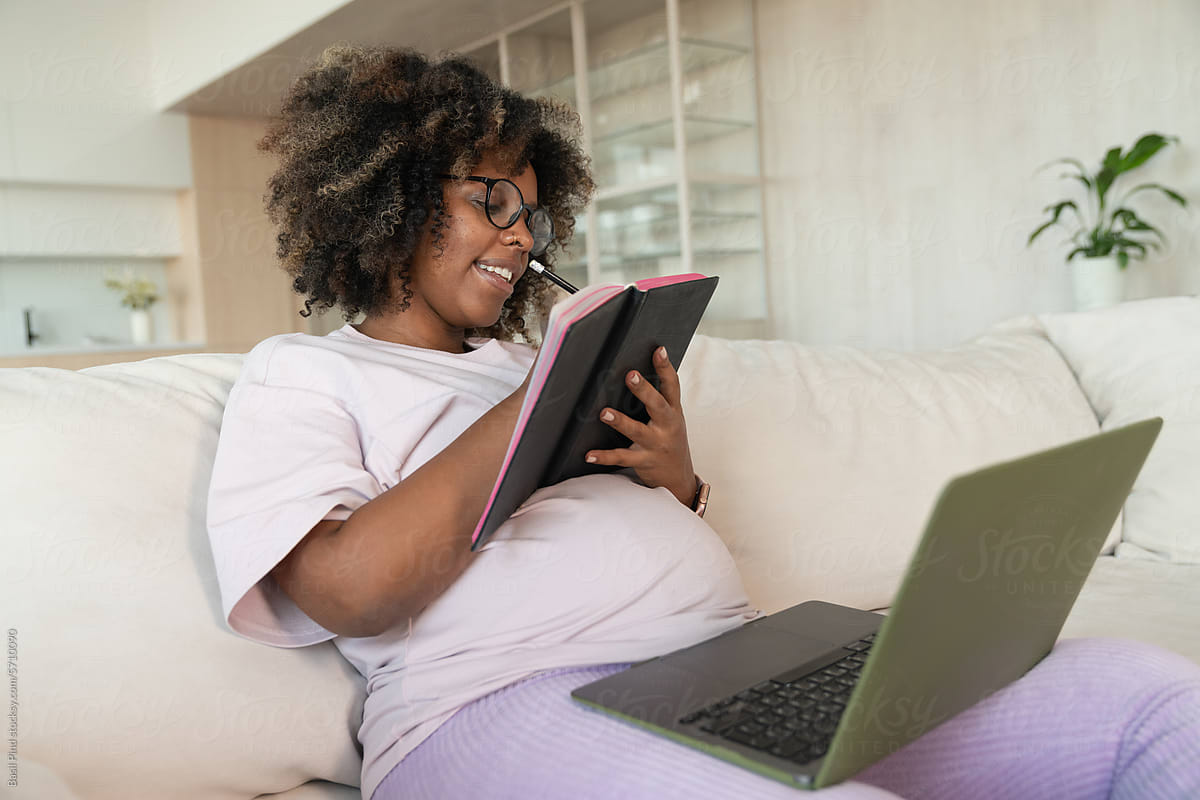 Pregnant woman working with laptop on couch