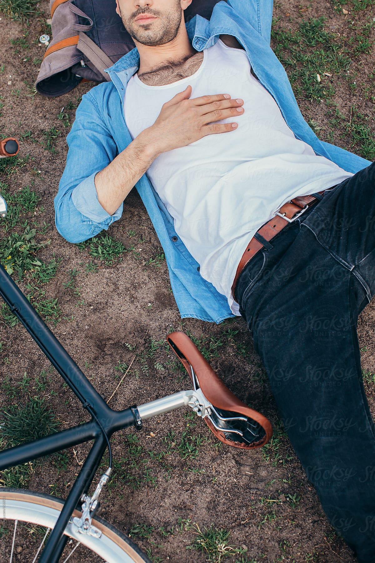 Caucasian Man Lying in Park With Head on Backpack Overhead