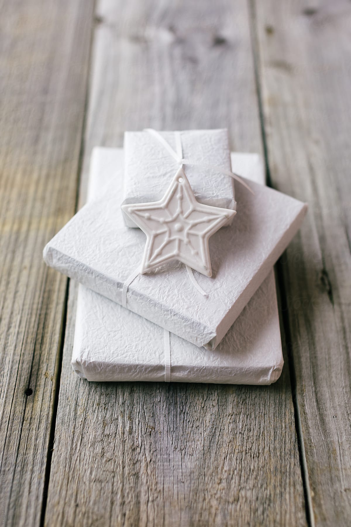 Stack of three white Christmas gifts on a rustic wood table