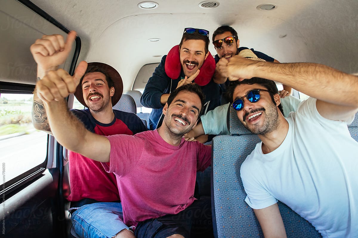 Group of young excited hipster men inside a van during a road trip