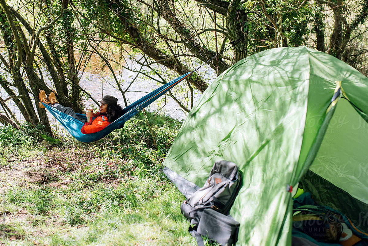 black woman in hammock at campsite with tent