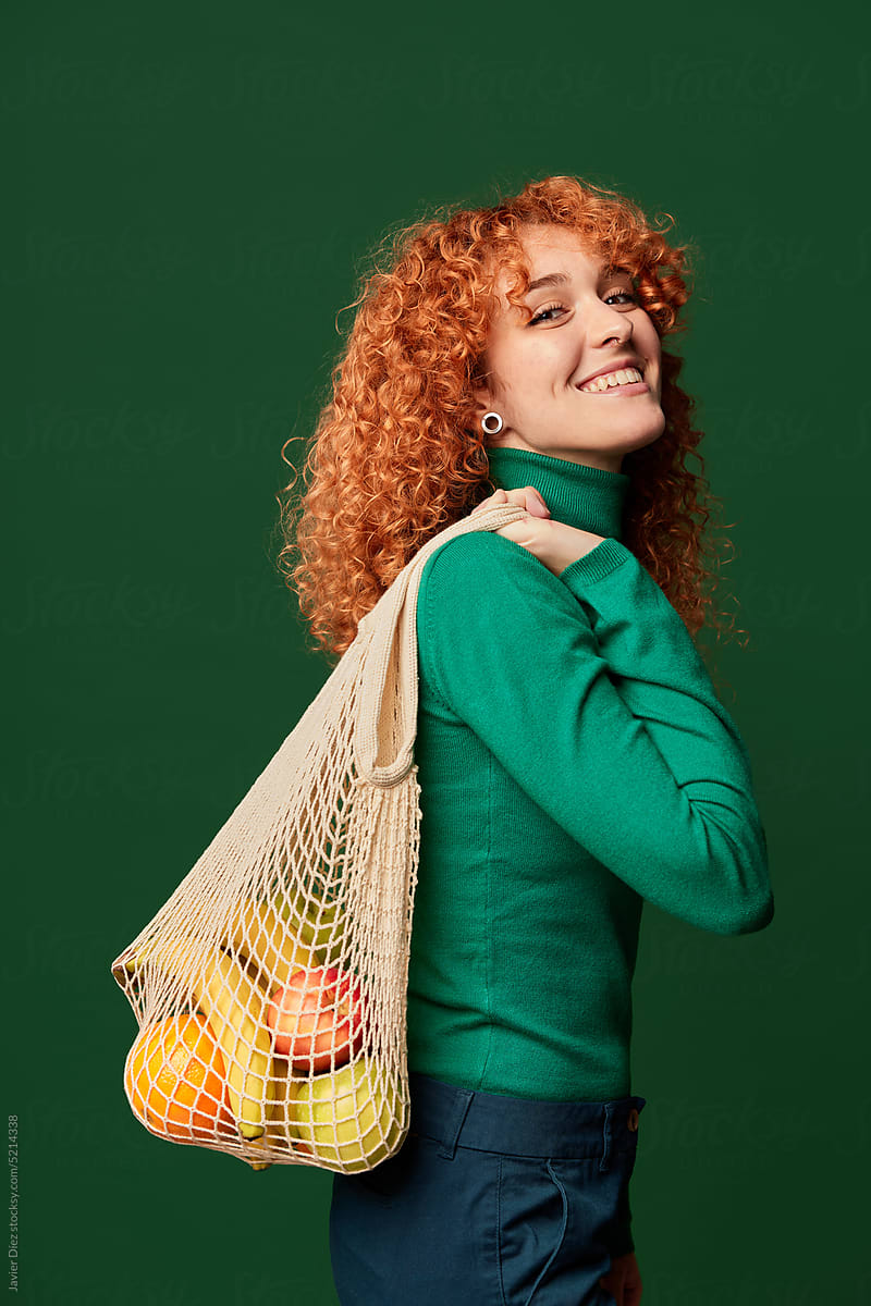 Content curly woman with heap of fresh fruit