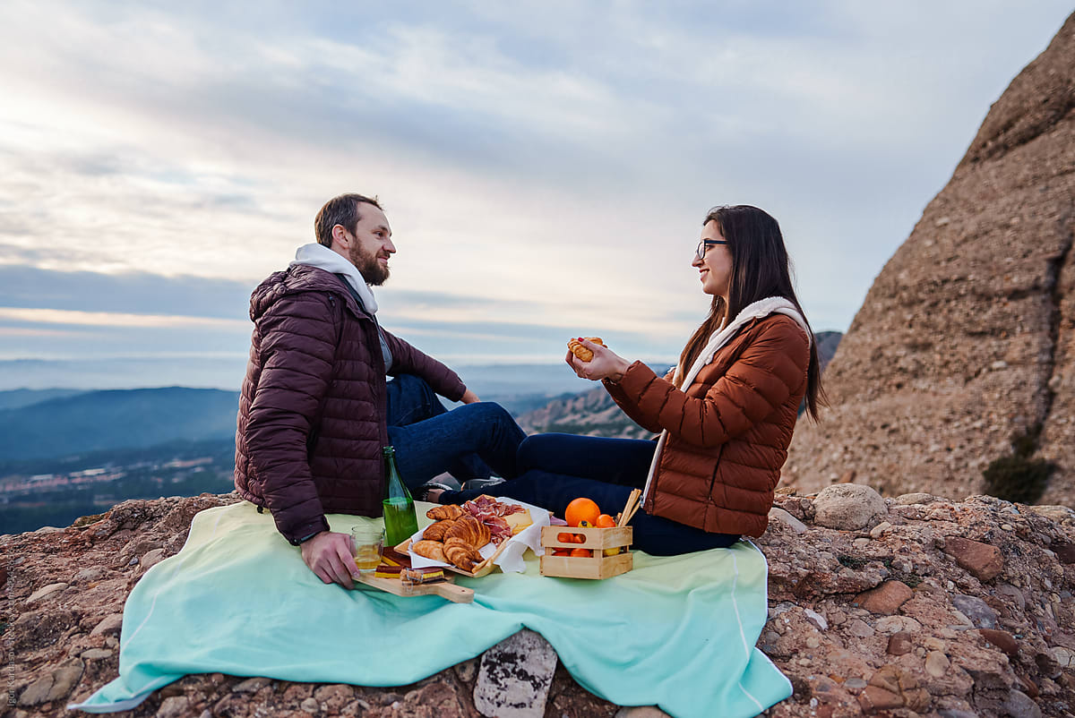 Couple enjoy romantic picnic on cliff edge in mountains