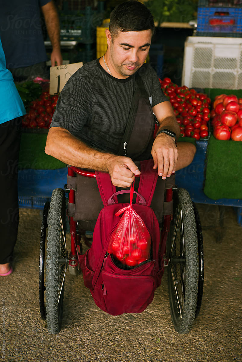 A man in a wheelchair at a fruit and vegetable street market