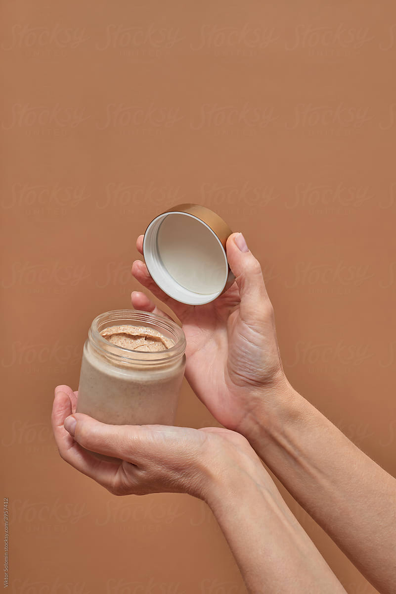Crop female opening jar with cosmetic product