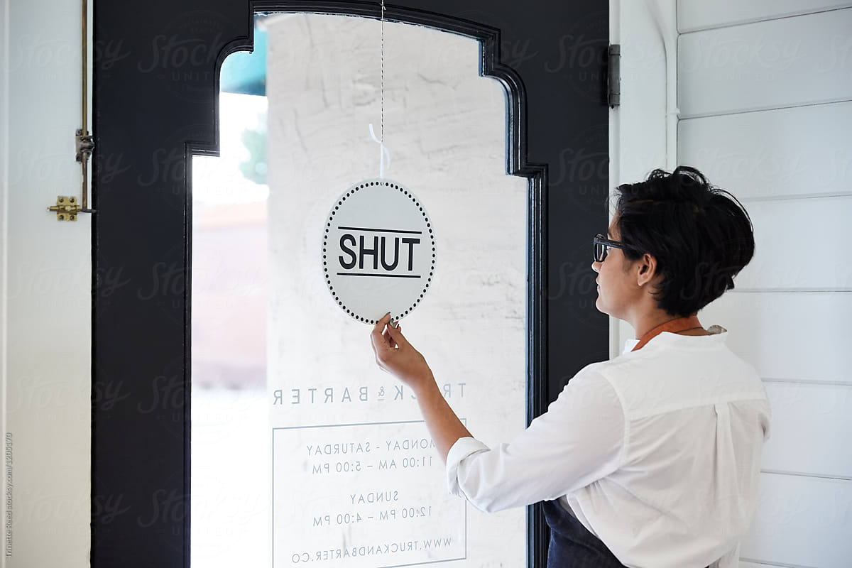 Millennial small business owner turning open/close sign in artisan retail store