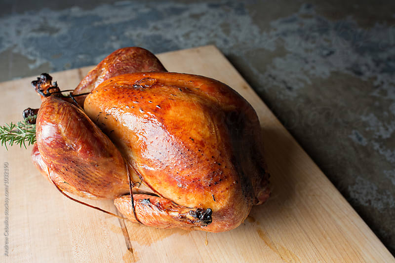 Whole roasted turkey on cutting board with golden brown skin and fresh herbs