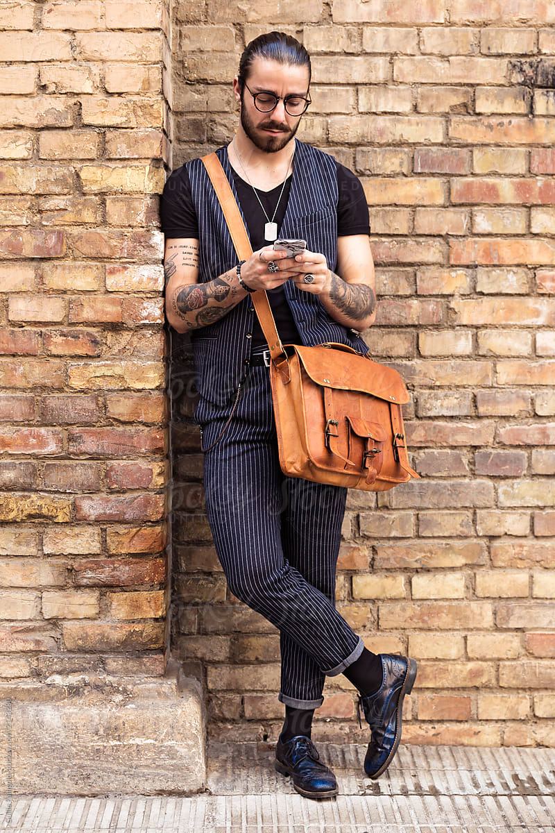 Stylish businessman with tattoos using mobile.
