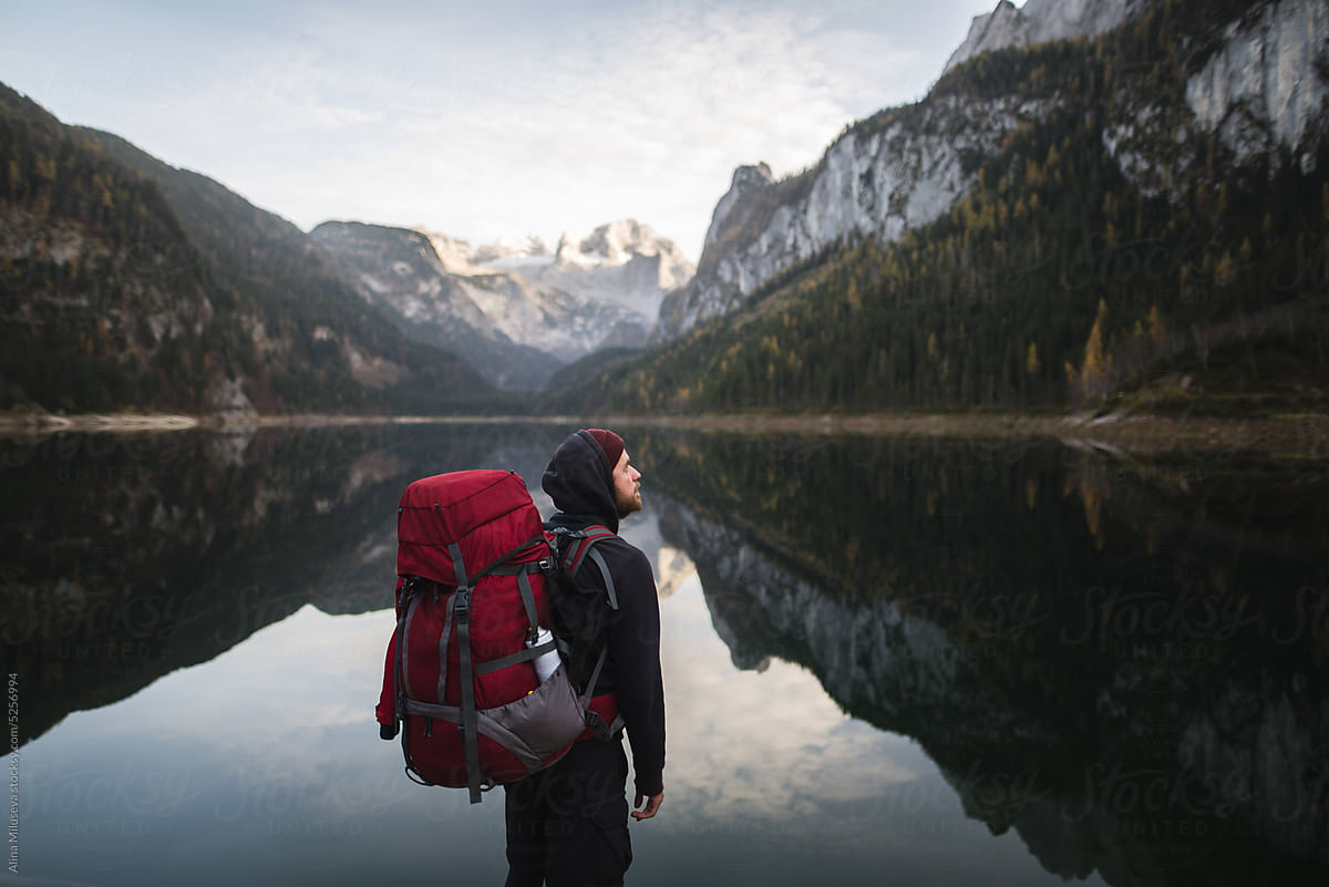 Traveler With Backpack Standing Near Lake And Mountains