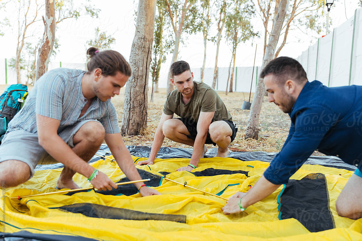 Group of friends putting the camping tent together