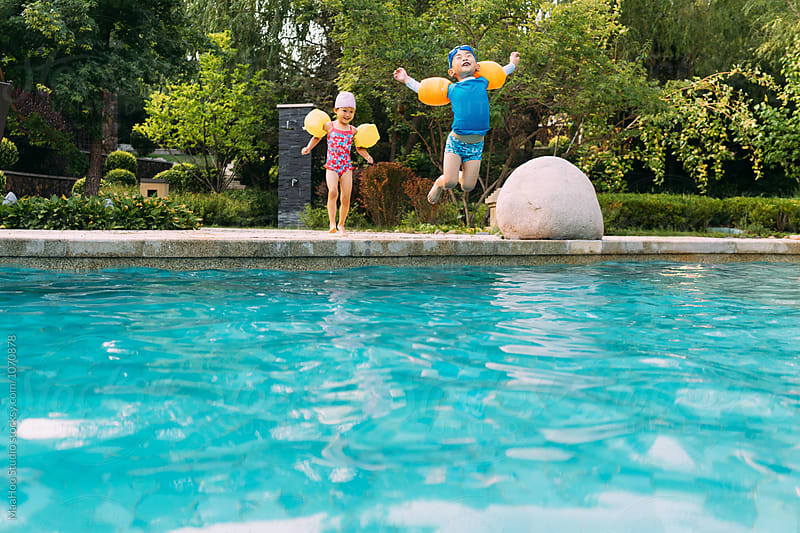 Two kids jumping into swimming pool