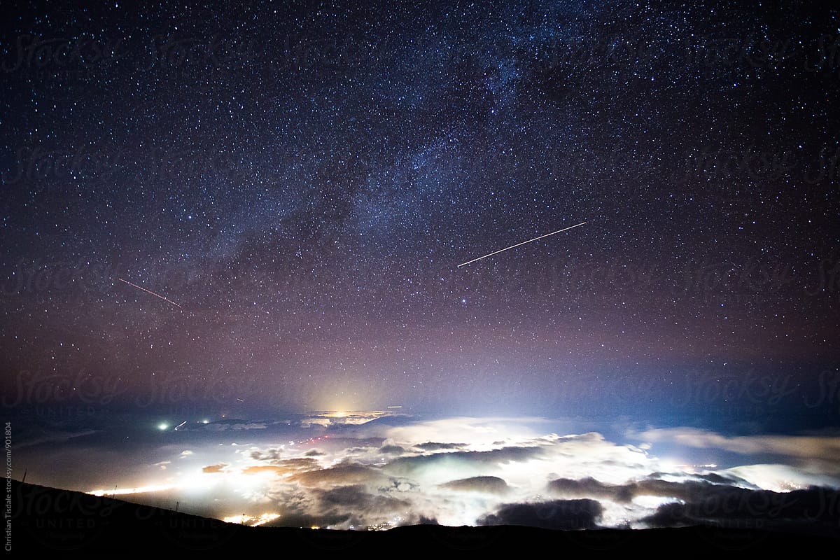 Milky Way rising over the lights of a cloud covered city