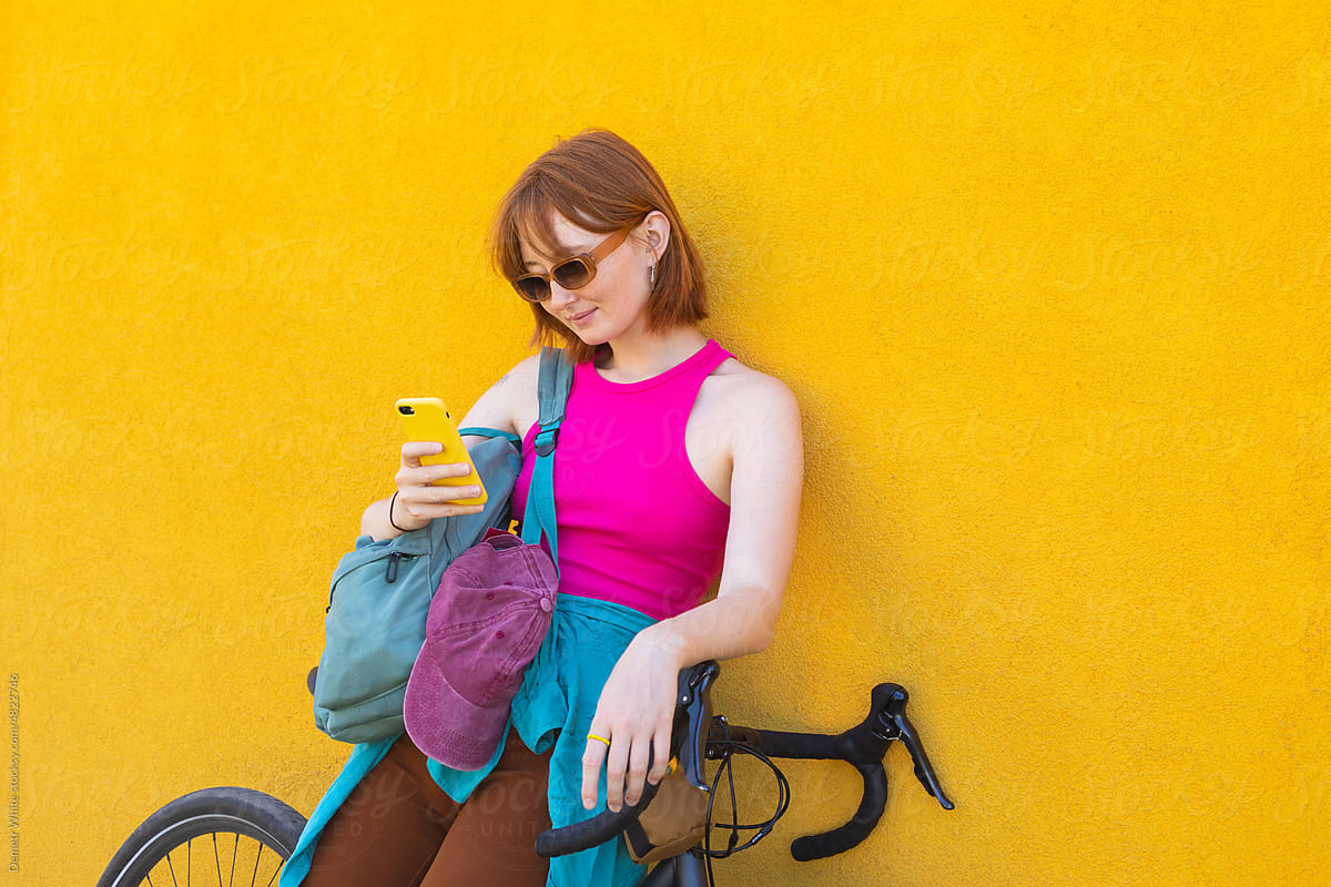 a girl sits on a bicycle frame and looks into a gadget