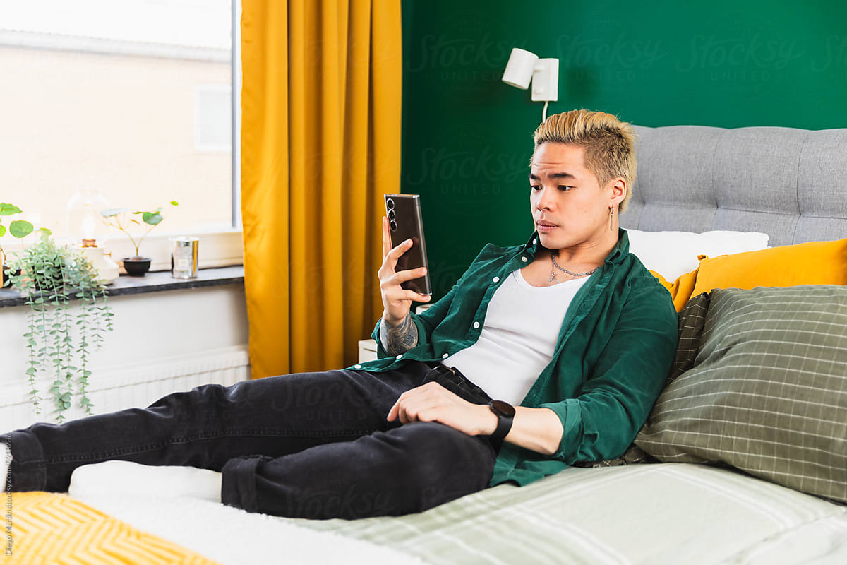 Man using phone while laying on the bed