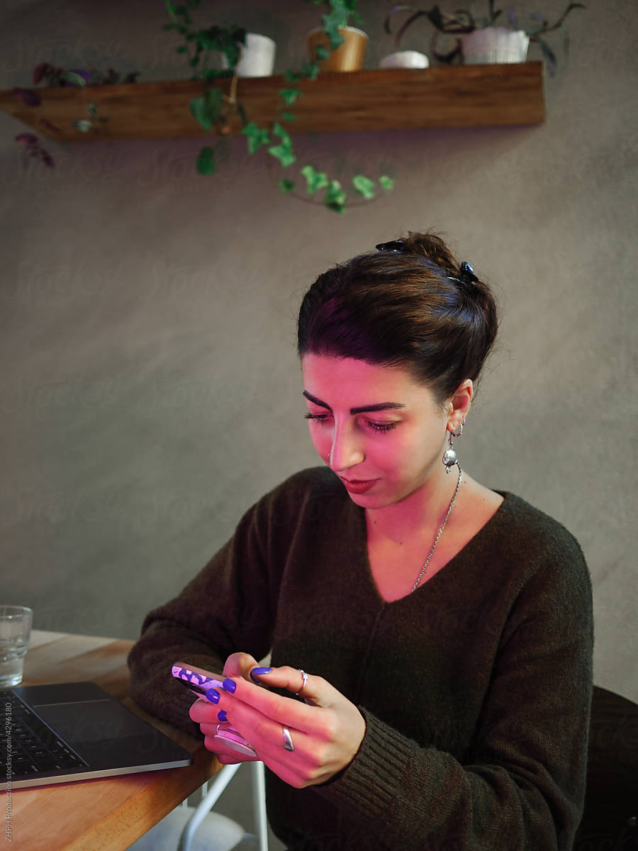 Young woman works on laptop and smartphone in cafe