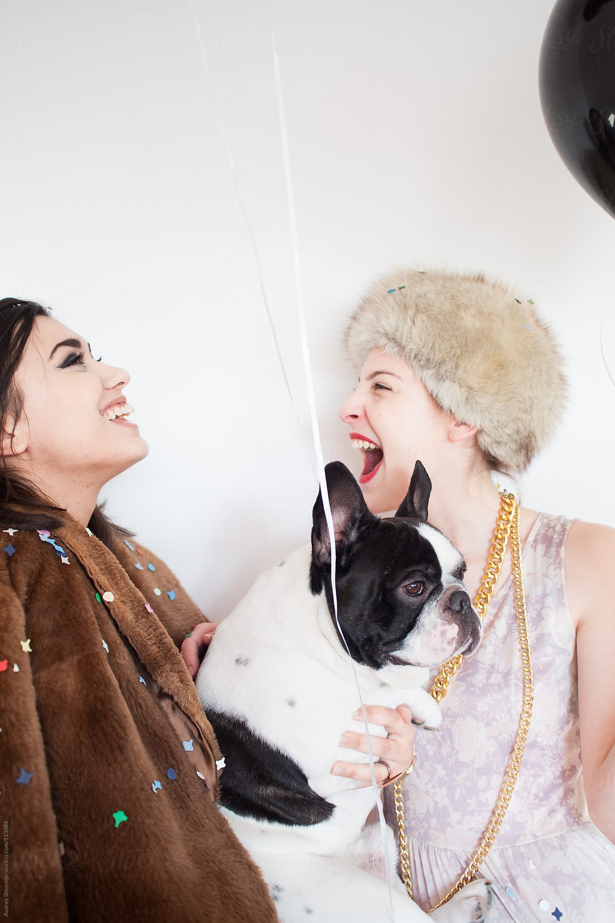 Two stylish women with french bulldog on party.